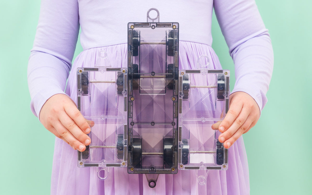Connetix Pastel magnetische tegels bovenaanzicht paarse wagon vastgehouden door kind groene achtergrond