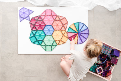 Kind legt kleurrijk mandalapatroon met Connetix Pastel Mega Pack 202pc magneet tegels op de vloer