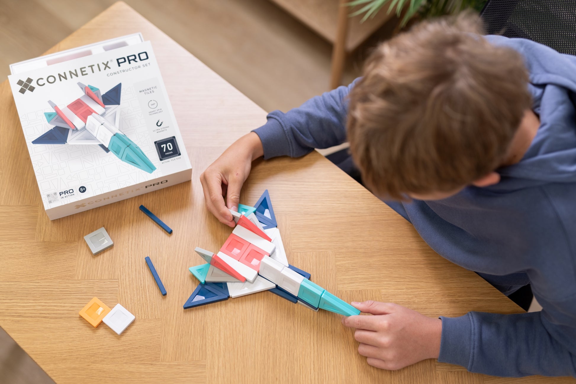 Jongen bouwt vliegtuig met Connetix PRO Constructor Set 70pc, magneten speelgoed met doos op tafel