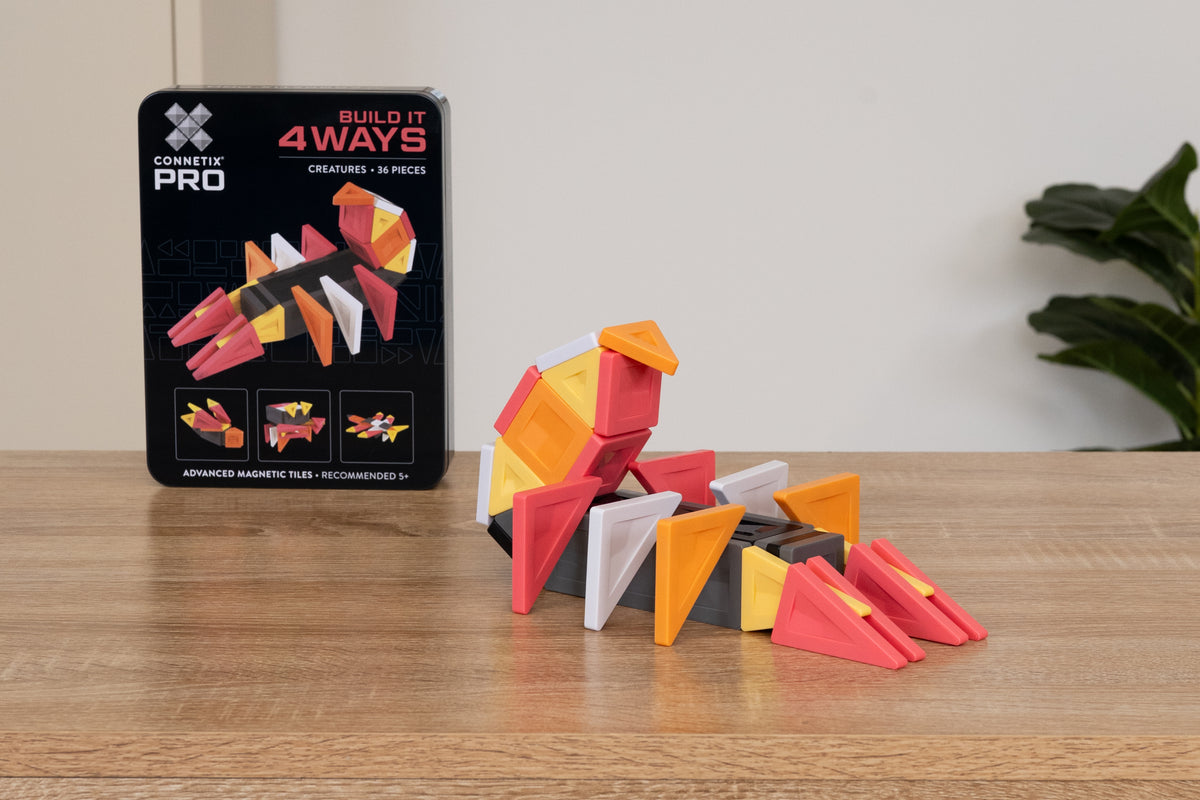 Connetix PRO Build It Creatures Pack kleurrijke dino gebouwd met magneet tegels naast verpakking