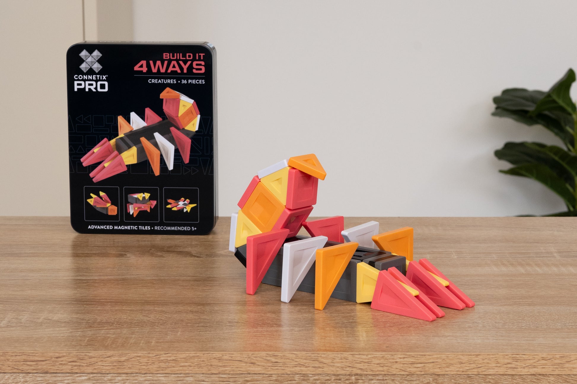 Connetix PRO Build It Creatures Pack kleurrijke dino gebouwd met magneet tegels naast verpakking