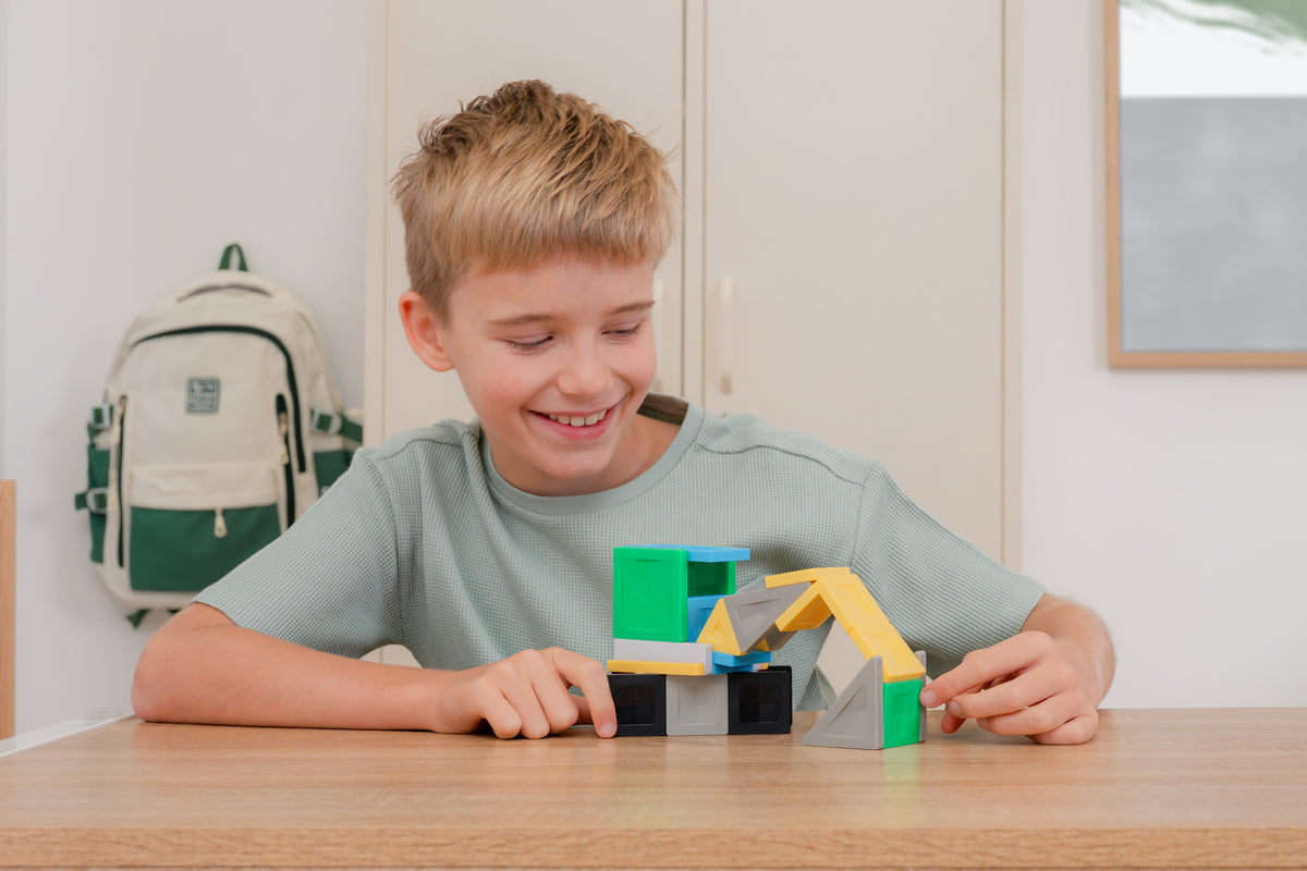 Connetix PRO magnetisch speelgoed: kind bouwt kleurrijk voertuig met gele en groene magneet tegels