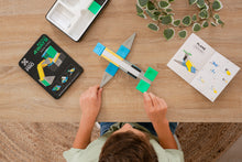Connetix PRO Build It 4 Ways: bovenaanzicht kind bouwt vliegtuig met instructieboekje en magneet speelgoed