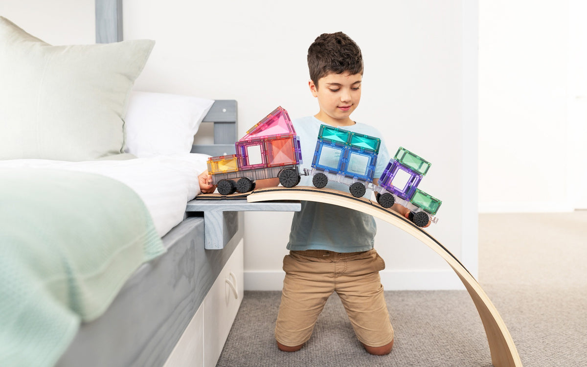 Connetix racebaan jongen spelend met pastel magneet speelgoed trein op houten boog slaapkamer setting