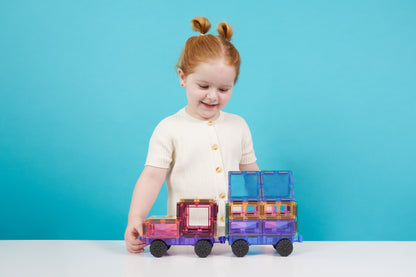 Kind bouwt met Connetix racebaan magnetische tegels trein in roze, paars en blauw op blauwe achtergrond