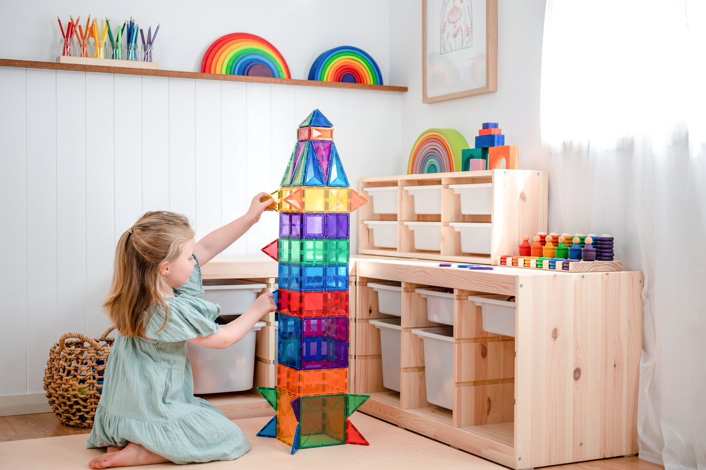 Meisje bouwt hoge toren met Connetix Rainbow Creative Pack 102pc magnetisch speelgoed in kleurrijke speelkamer