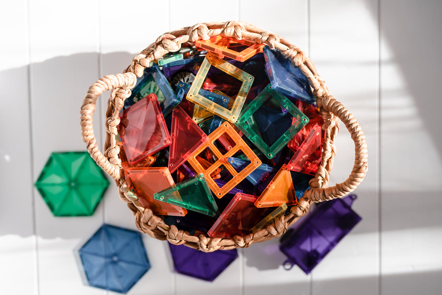 Bovenaanzicht van rieten mand vol kleurrijke Connetix Rainbow Mega Pack 212pc magnetische bouwstenen en tegels