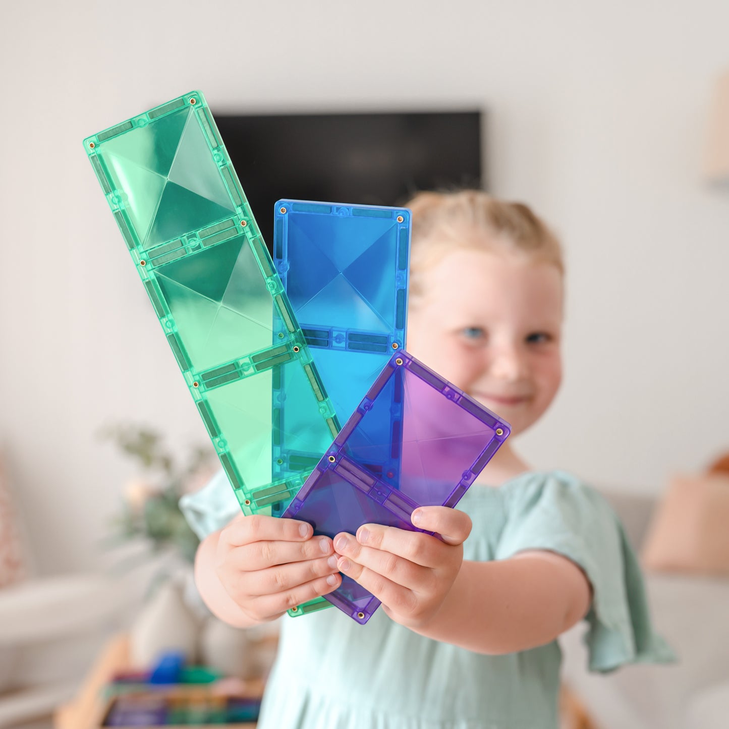 Kind toont Connetix Rectangle magnetische tegels in groen, blauw en paars tijdens creatief speelmoment