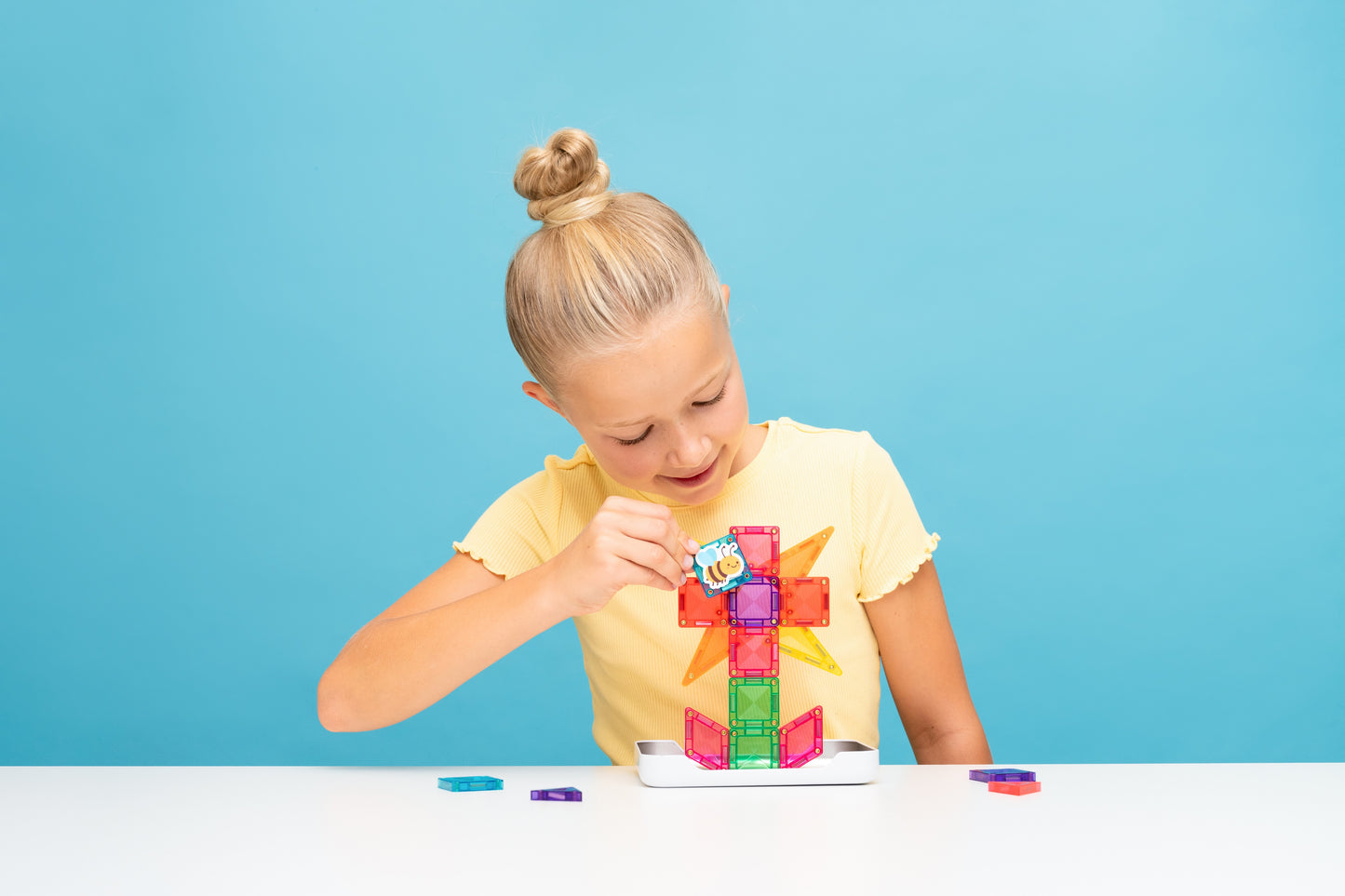 Connetix travel mini pack kind met geel shirt bouwt toren met kleurrijke magneet tegels en sticker