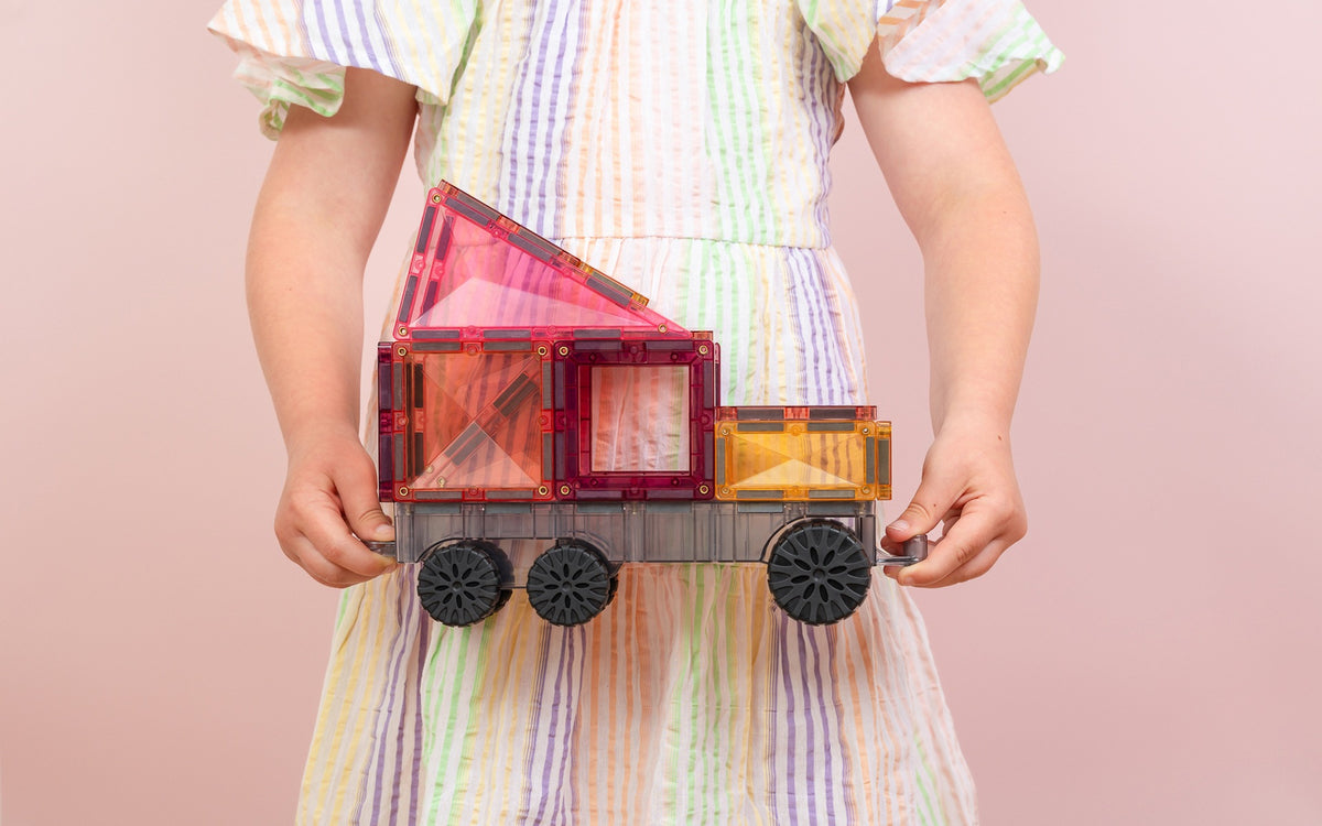 Connetix Transport Pack pastel vrachtauto magnetische tegels vastgehouden door kind roze achtergrond