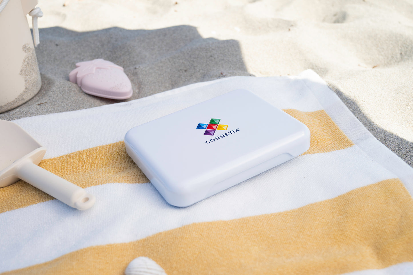 Connetix travel mini pack gesloten witte koffer met logo op gestreepte strandhanddoek