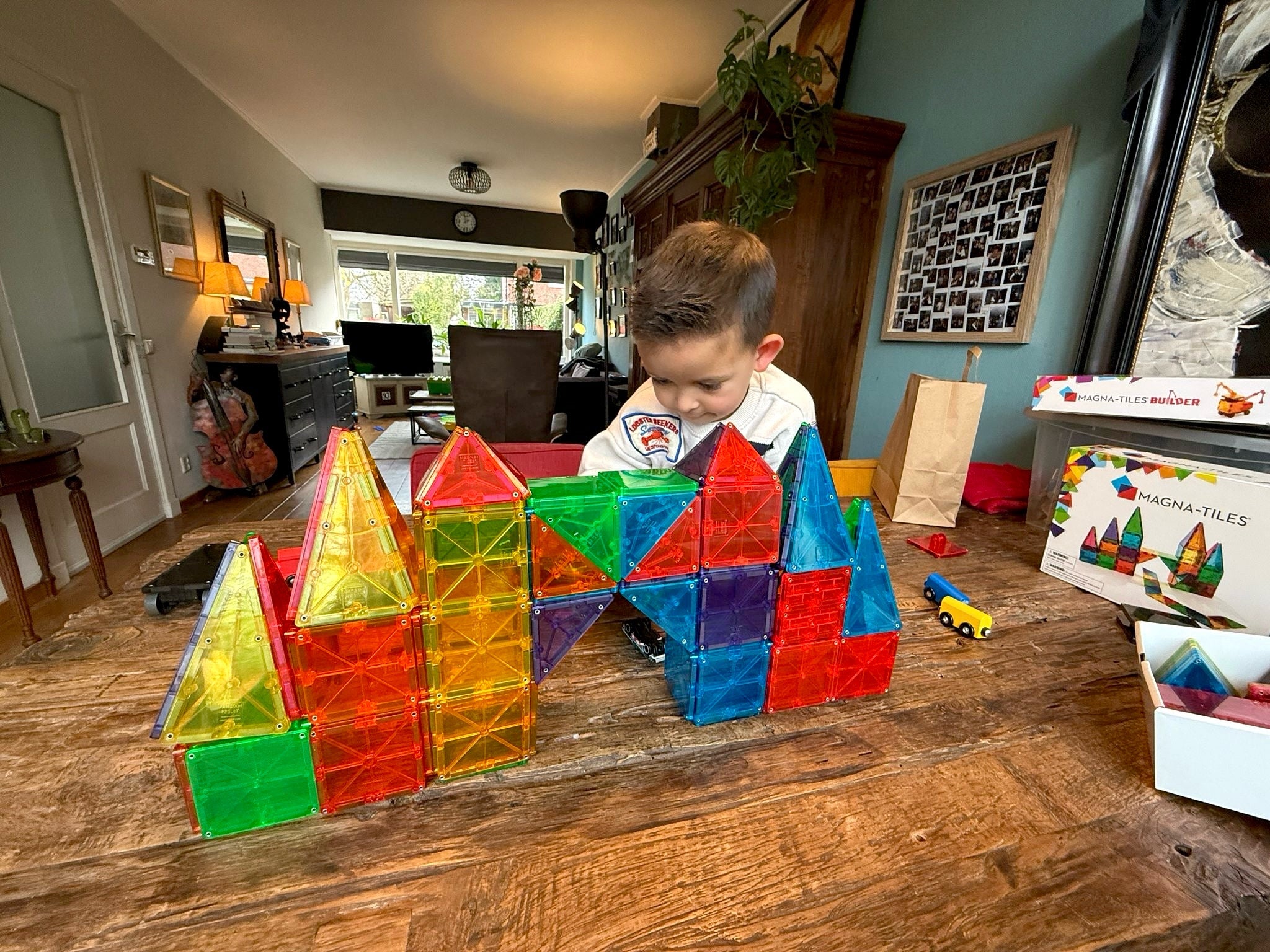Kind speelt op tafel met een toren grote kasteel van magna-tiles magnetische bouwstenen.