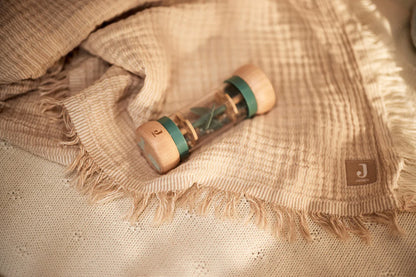 Educatief peuter speelgoed van Jollein: houten rammelaar met blauwe tinten, liggend op een beige hydrofiele doek.