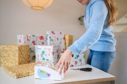 Eigenaar Ruby bereidt kraamcadeau voor met plakbandhouder, cadeaupapier jungleprint zichtbaar