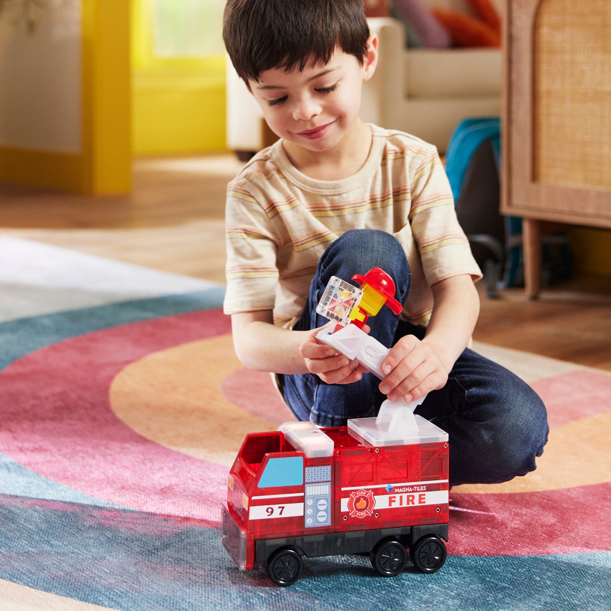 Magnetic magna tiles Fire Station jongen speelt met magnetische brandweerwagen en brandweerman figuur thuis