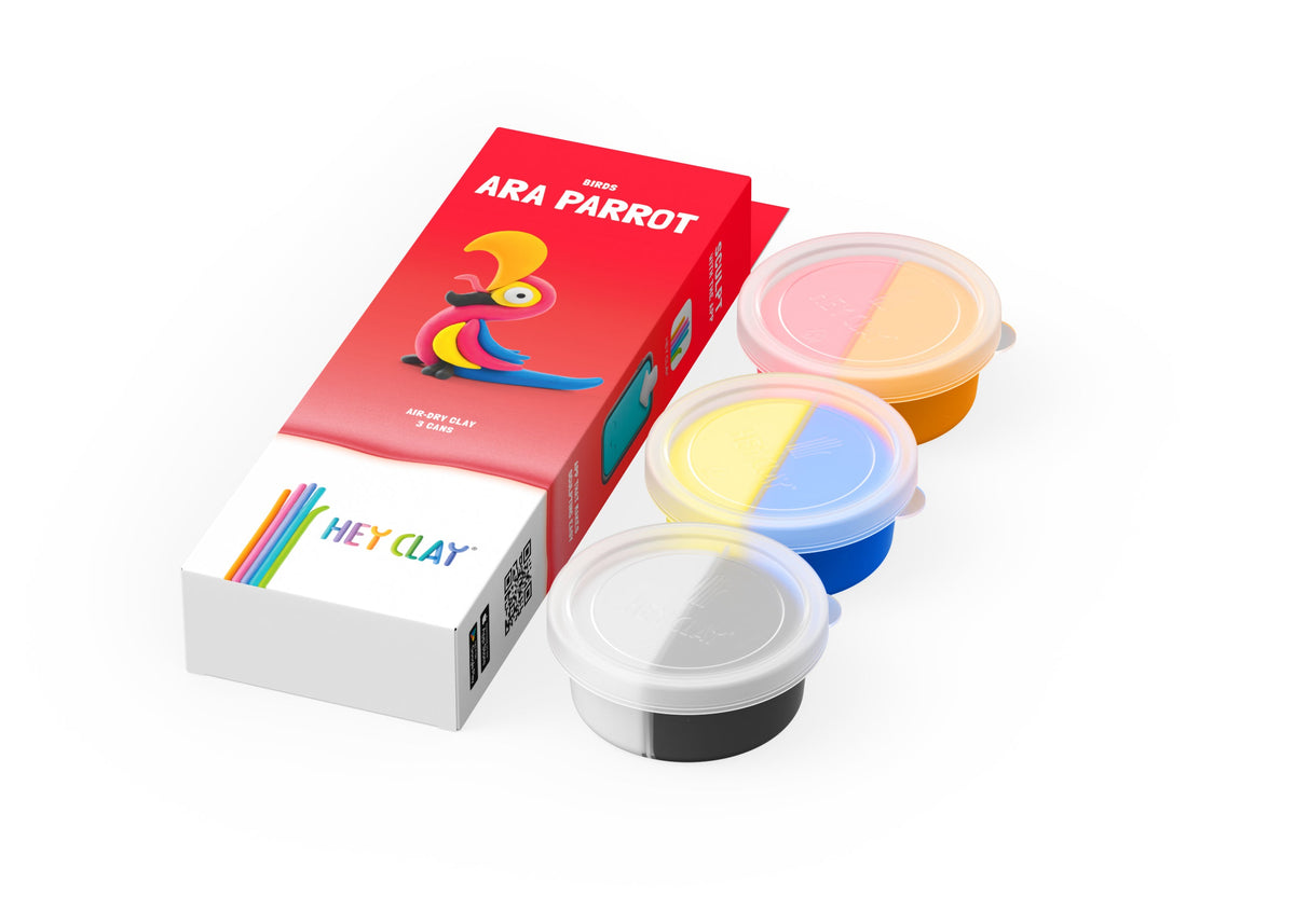 Hey Clay Birds Ara Parrot set met 3 potjes boetseerklei in geel, roze en blauw naast rode verpakking