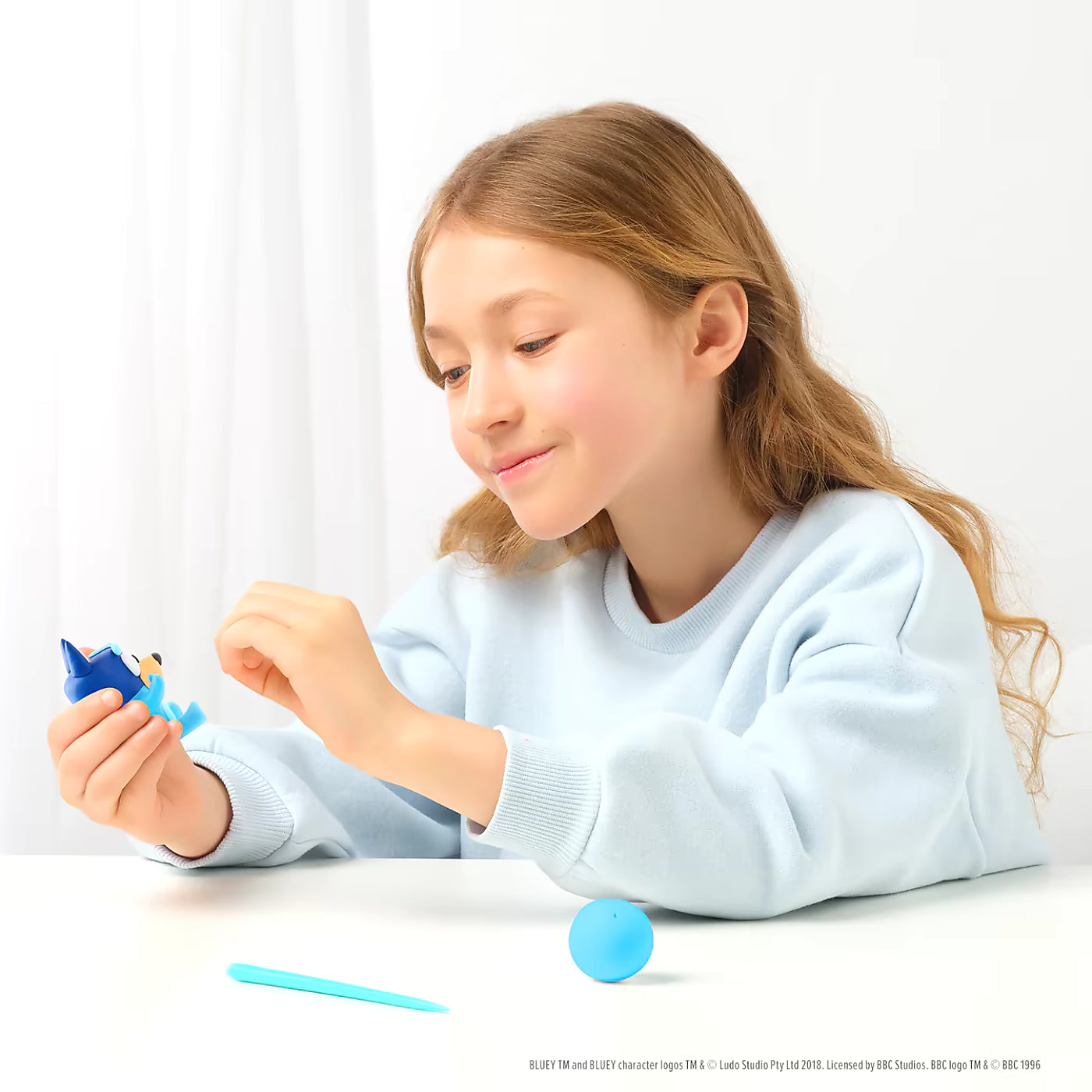 Kind speelt en boetseert Bluey figuur uit Hey Clay Bluey & Friends speelgoedset met 15 potjes boetseerklei.