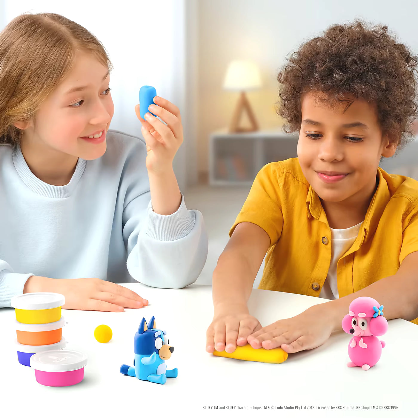 Twee kinderen maken Bluey en Coco met Hey Clay Bluey & Friends boetseerklei set met vrolijke potjes en tools.