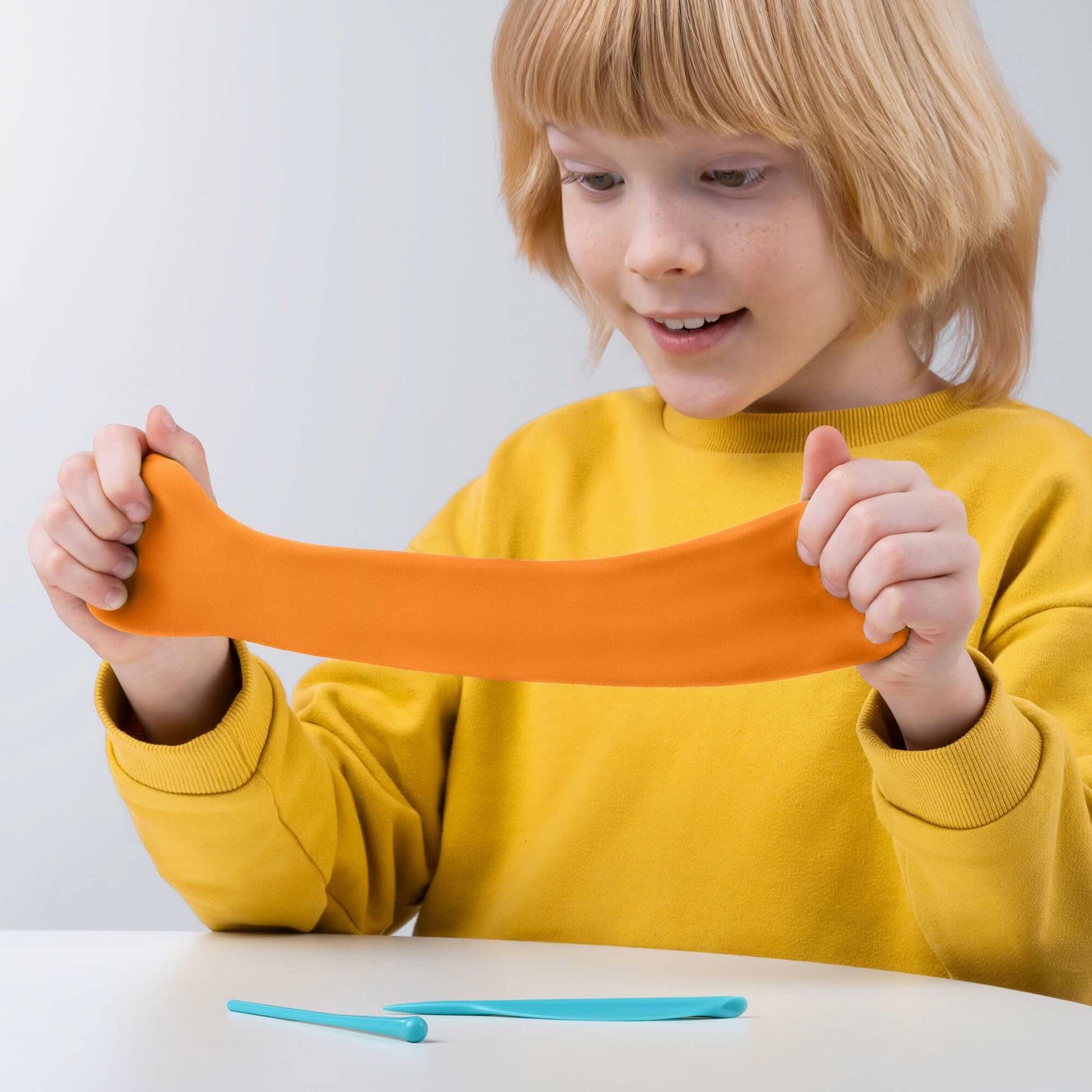 Kind speelt met oranje Hey Clay boetseerklei, leuk en educatief speelgoed met creatieve klei ideeën voor kinderen.