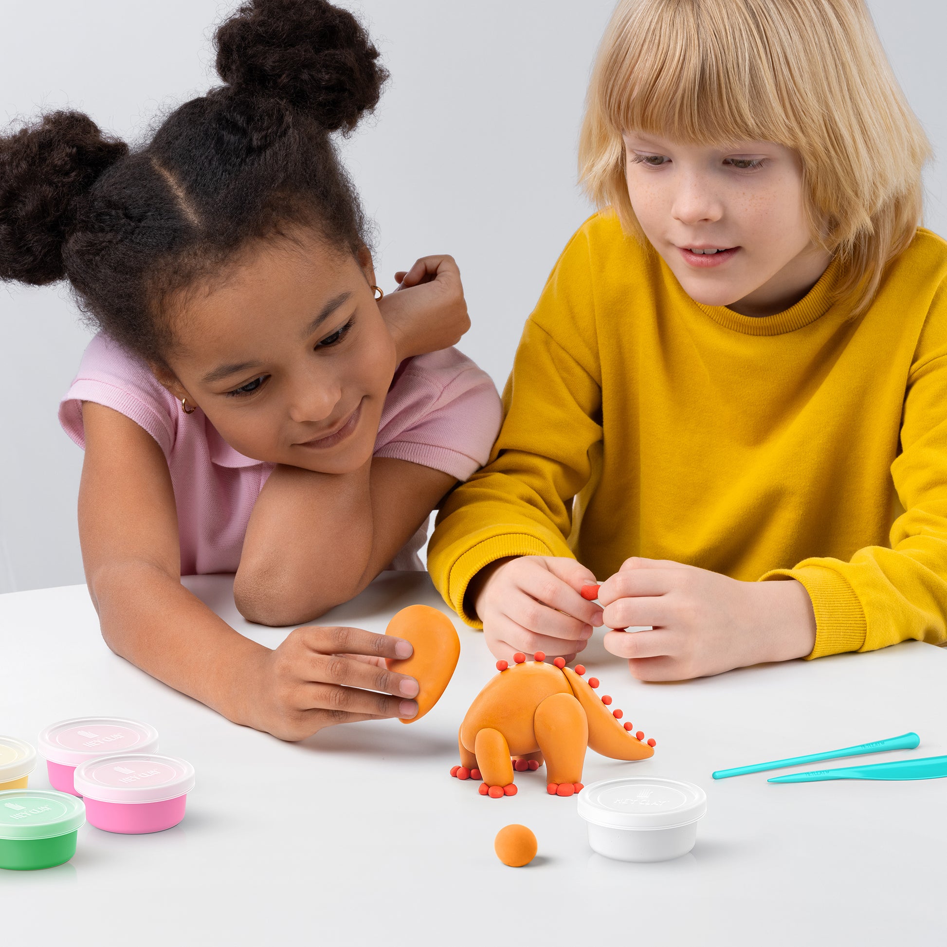 Hey Clay kinderen boetseren samen oranje dinosaurus speelgoed met kleurrijke boetseerklei potjes