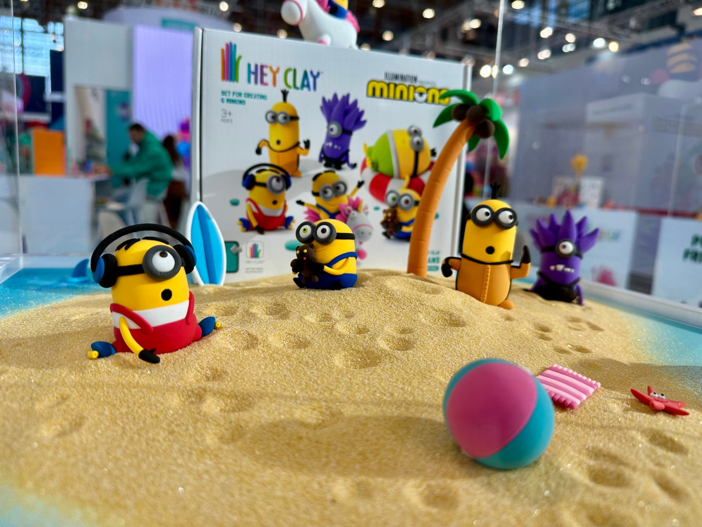 Hey Clay Minions boetseerklei figuren op stranddisplay met verpakking en zandscène op speelgoedbeurs spielwaremesse 2026