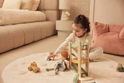 Peuter speelt op rond kleed met houten auto van Jollein, een veilige en leuke keuze voor baby speelgoed of cadeau.
