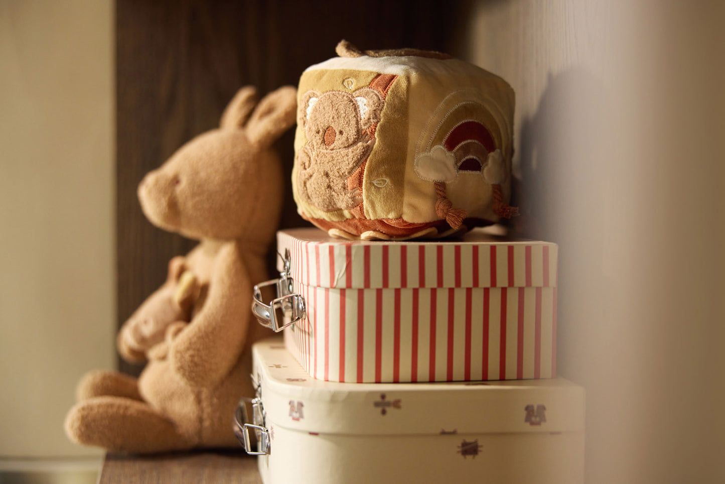 Jollein activiteitenkubus met koala op gestreepte opbergdoos naast kangoeroe knuffel in kinderkamer.