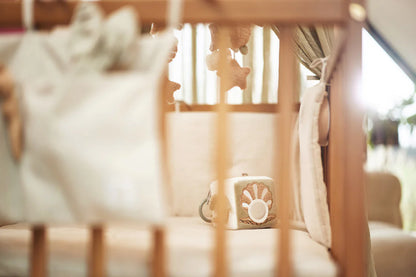 De Jollein activiteitenkubus Deepsea ligt in een houten ledikant, met zichtbare spiegel en schelpdesign voor sensorisch spel.