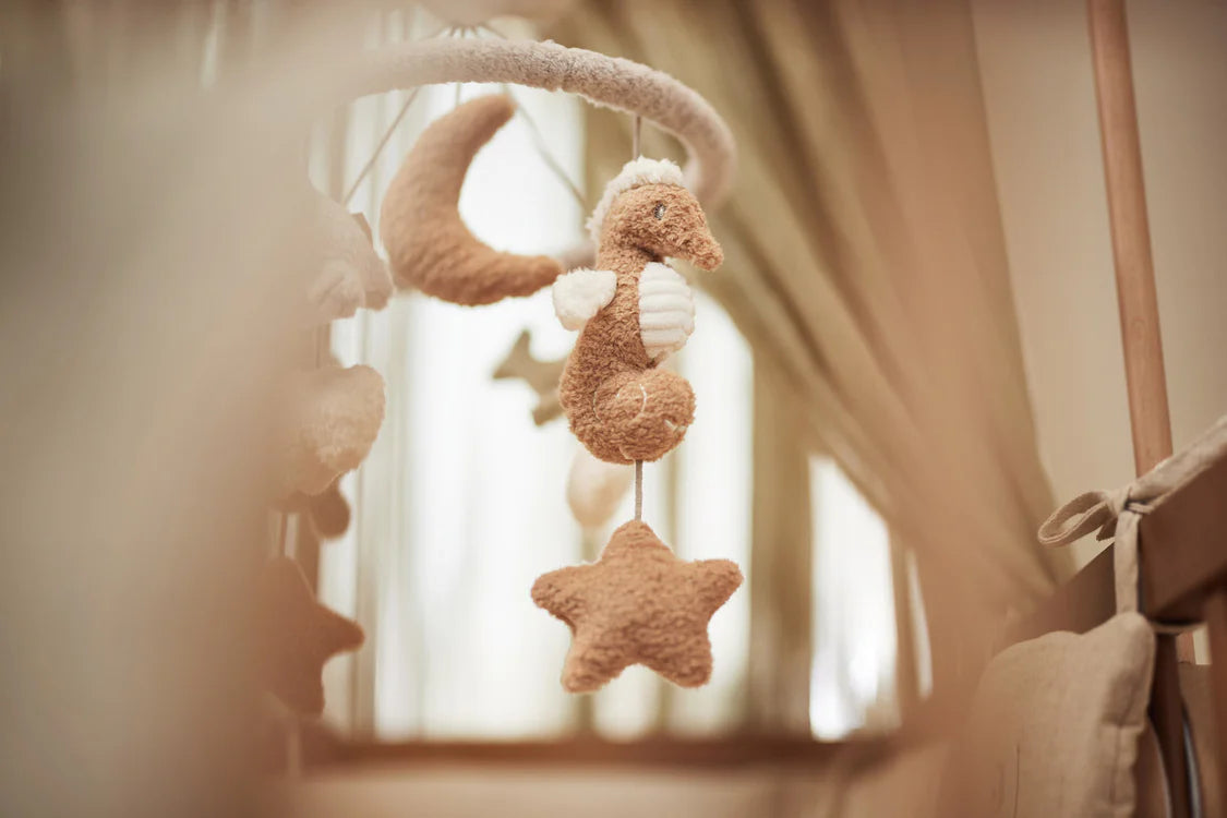 Sfeervolle opname van het zeepaardje van de Jollein Baby Mobiel Deepsea boven het babybedje.