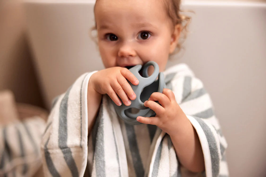 Baby speelt en bijt op Sea Green bijtring bal van Jollein, ideaal als kraamcadeau of baby speelgoed.