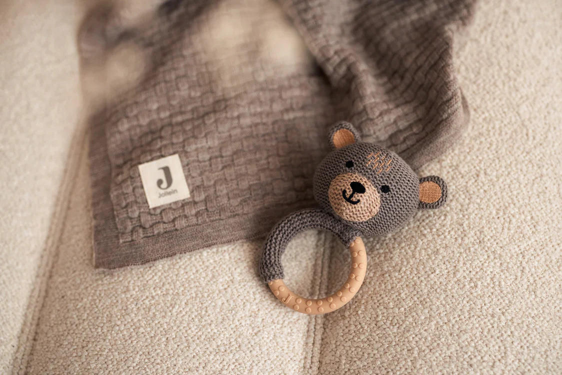 Gehaakte Jollein bijtring beer op beige bank met bruine gebreide deken, schattig baby speelgoed in neutrale stijl.