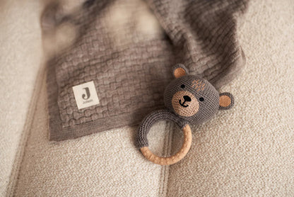 Gehaakte Jollein bijtring beer op beige bank met bruine gebreide deken, schattig baby speelgoed in neutrale stijl.