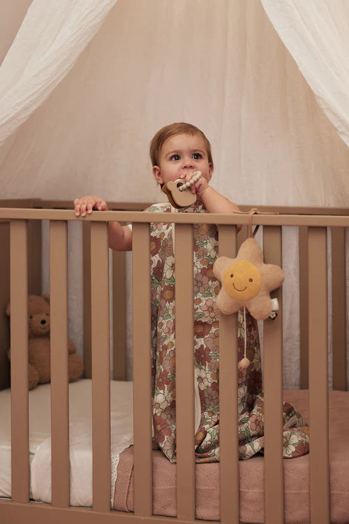 Baby staat in ledikant met siliconen Jollein Bijtring Teddy Bear in hand, stijlvol baby cadeau voor dagelijks gebruik.