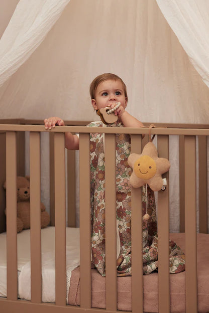 Baby staat in ledikant met siliconen Jollein Bijtring Teddy Bear in hand, stijlvol baby cadeau voor dagelijks gebruik.