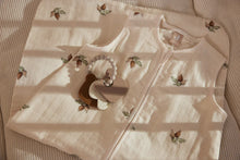 Jollein Bijtring Teddy Bear ligt op crème slaapzak met print, perfect als natuurlijk kraamcadeau of baby cadeau.