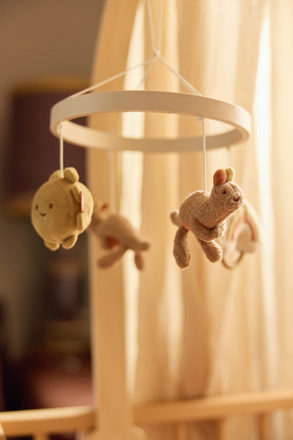 Jollein baby mobiel Roarsome sfeerbeeld in babykamer: pluche zon en konijn hangen aan houten ring, educatief speelgoed.