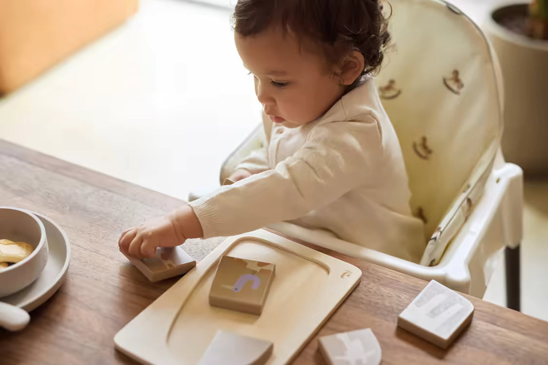 Baby plaatst blokjes in Jollein Houten puzzel Giraffe, vormenpuzzel van speelgoed hout met educatieve waarde.