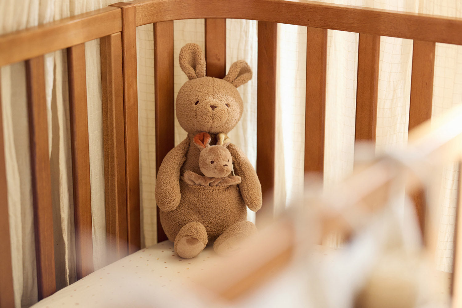 Jollein Kangaroots kangoeroe knuffel staand in houten ledikant, lief kraamcadeau voor pasgeboren baby