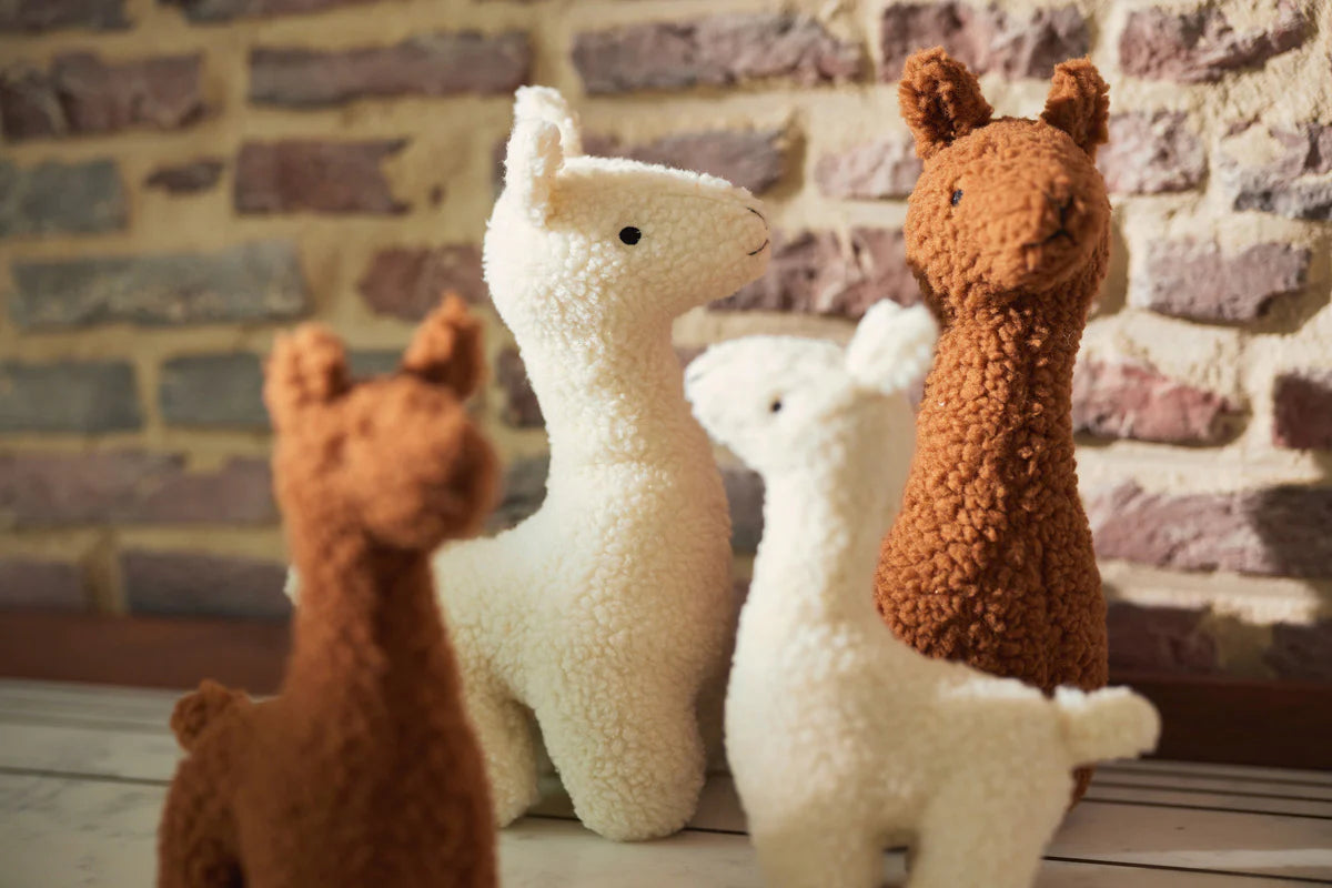 Jollein knuffel lama’s in off-white en caramel, samen als set afgebeeld tegen een bakstenen muur.