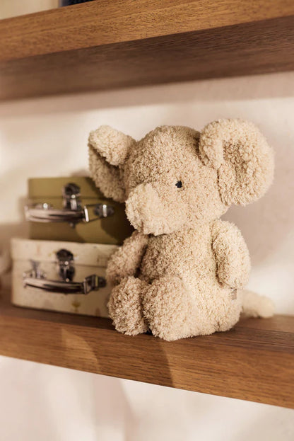 Zittende Jollein knuffel olifant op houten plankje naast koffertjes, decoratief en geschikt als baby cadeau of kraamcadeau.