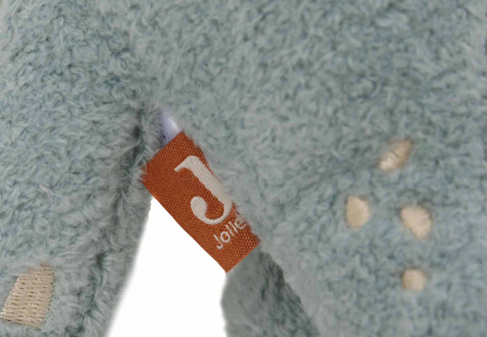 Detail van zachtblauwe Jollein Knuffel Roarsome met roestkleurig label, perfect als kraamcadeau voor baby’s.