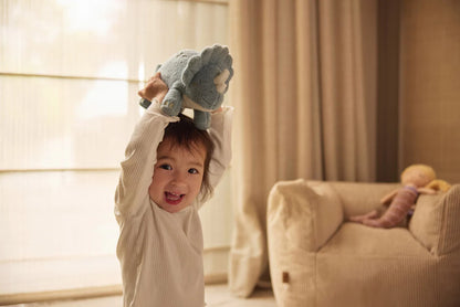 Kind speelt blij met Jollein Knuffel Roarsome dinosaurus in blauw, zacht speelgoed dino voor baby’s.