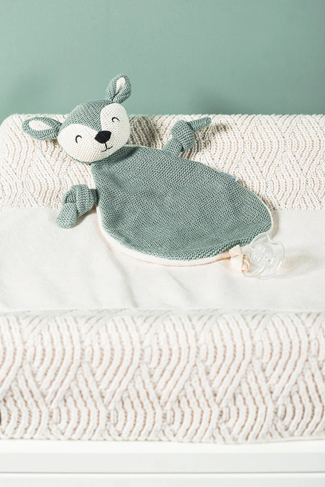 Jollein speenknuffel deer in Ash Green ligt op een babybedje, perfect als knuffeldoekje of baby cadeau.