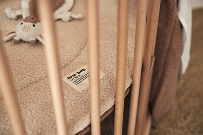 Jollein giraffe knuffeldoekje ligt knus in een houten babyledikant, ideaal als lief kraamcadeau.