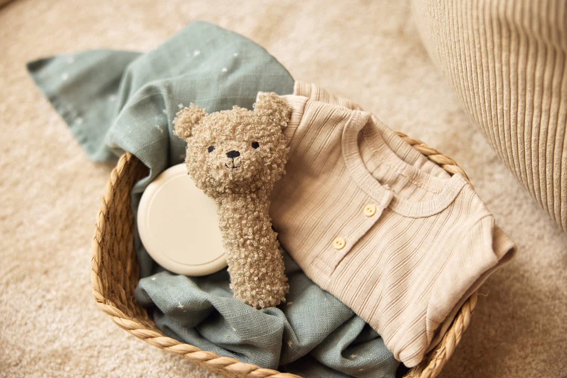 Jollein rammelaar Olive Green in mand met babykleding, ideaal als kraamcadeau of baby cadeau voor pasgeborenen.