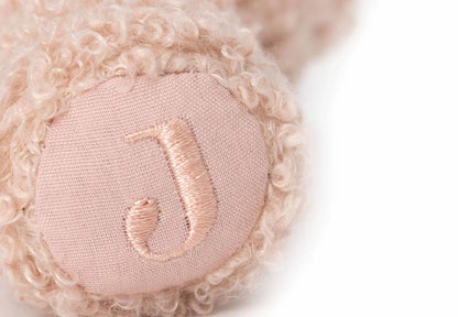 Detailopname van de Jollein rammelaar Wild Rose met roze J-borduursel op zachte teddy stof voor baby speelgoed.