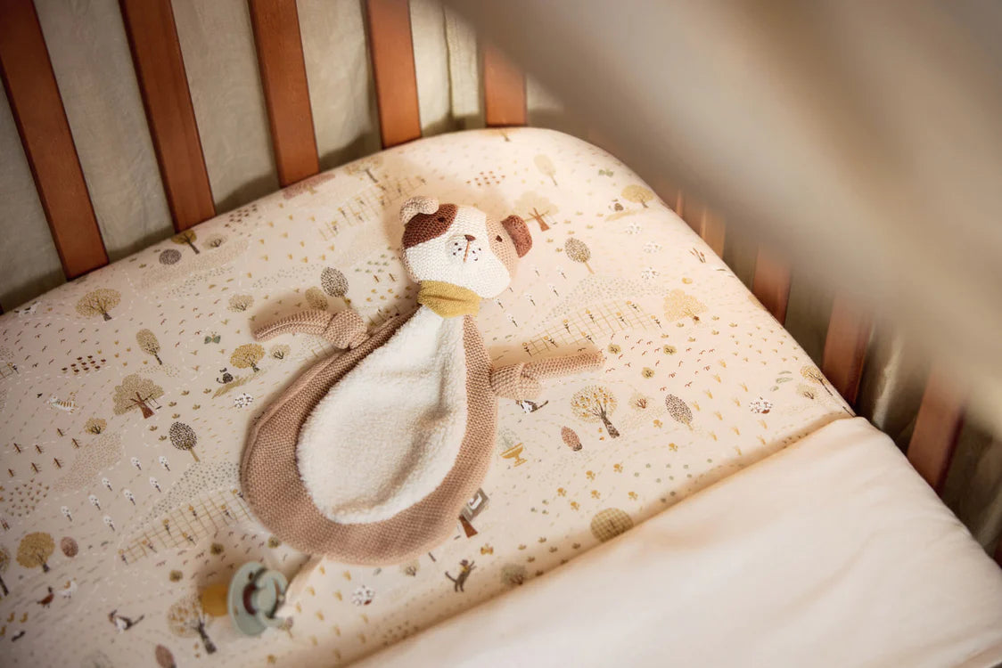 Jollein Speendoekje Mick hondje ligt in wieg op beddengoed met boomprint, zacht knuffeldoekje.