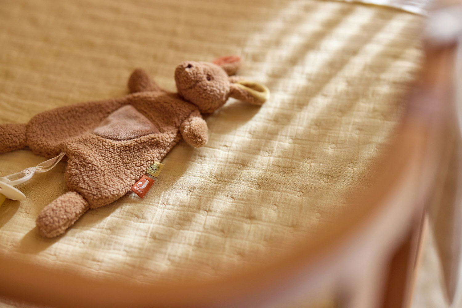 Jollein speenknuffel konijn camel liggend op aankleedkussen, ideaal zacht baby cadeau voor pasgeborenen.