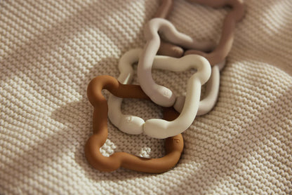 Meerdere siliconen Jollein bijtringen in teddy bear vorm op een gebreide ondergrond, perfect als box speelgoed.