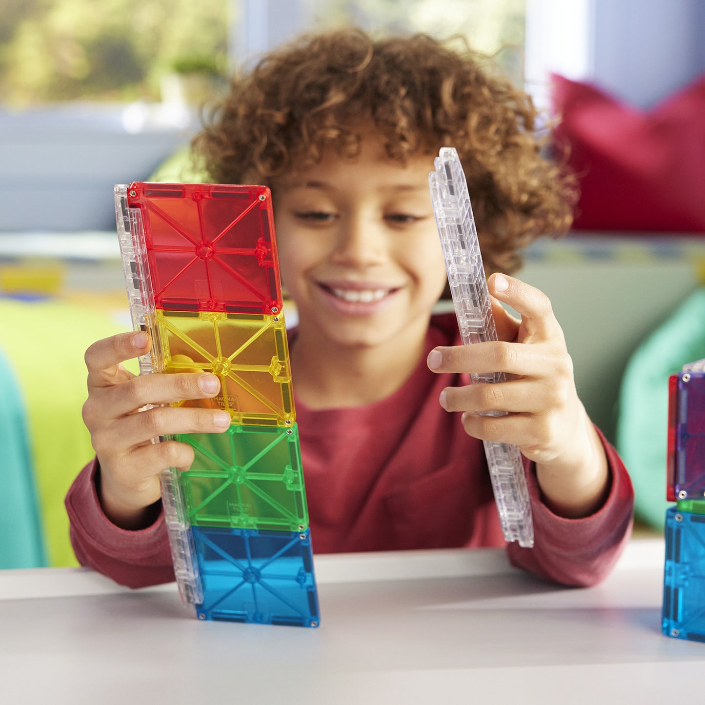 Jongen bouwt magna tiles knikkerbaan met magnetische rails en kleurrijke MicroMags blokken